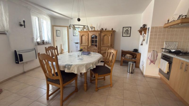 Küche in einem Einfamilienhaus mit rundem Tisch, Holzstühlen und Kredenz.