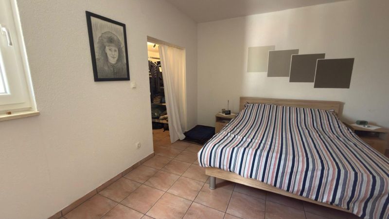 Schlafzimmer mit Keramikfliesen, Wandzeichnung und Bett in einem Einfamilienhaus.