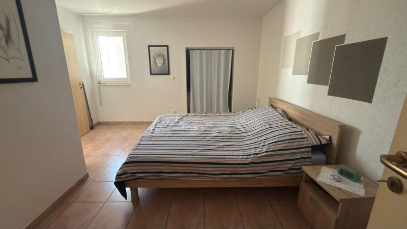 Schlafzimmer in einem Einfamilienhaus mit Bett, Keramikboden und minimalistischem Dekor.