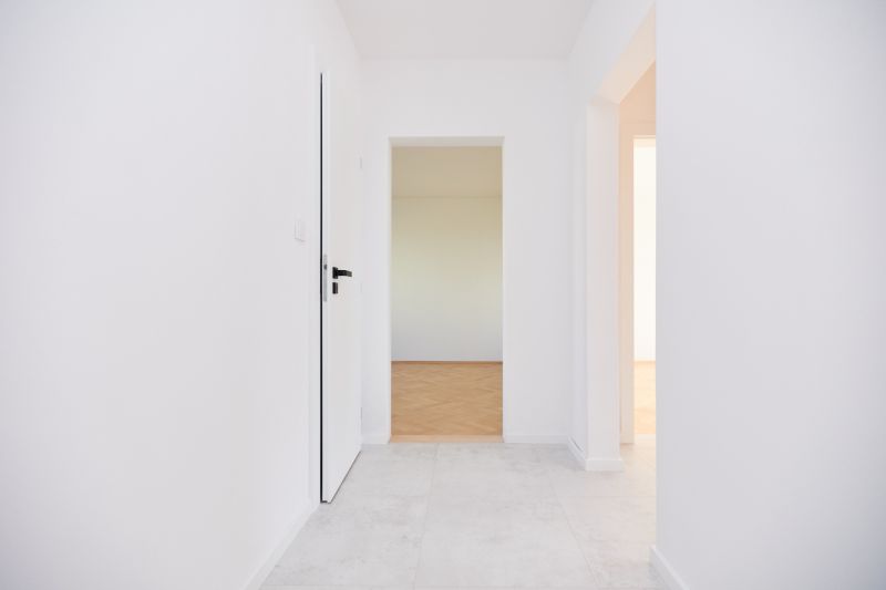 Ein Flur in einer 3-Zimmer-Wohnung mit weißen Wänden und einem Boden in Holzoptik.