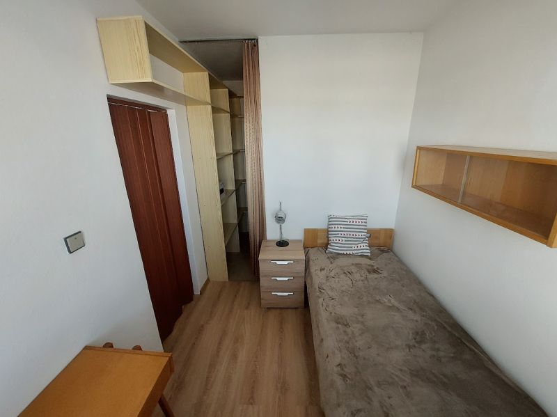 Ein Zimmer in einer Einzimmerwohnung mit Holzboden, Bett und Regalen.