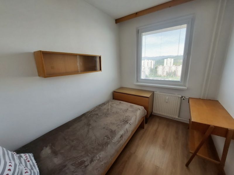 Ein Zimmer in einer Einzimmerwohnung mit einem Holzboden, einem Bett und Möbeln.