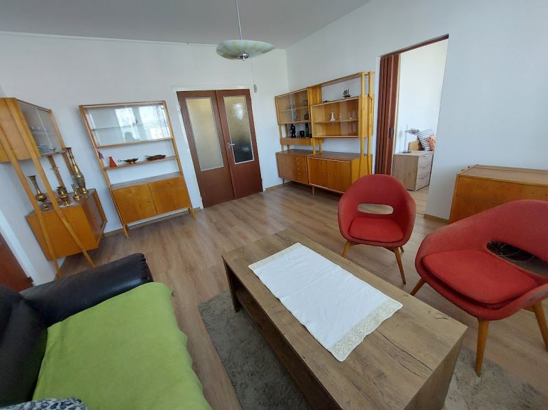 Wohnzimmer einer Einzimmerwohnung mit Holzboden und Retro-Möbeln.