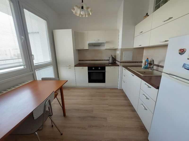 Küche in einer Einzimmerwohnung mit weißen Schränken und einem Holzboden.