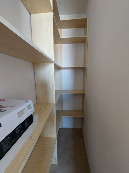 Ein schmaler Raum mit einem Regalsystem und Stauraum in einer Einzimmerwohnung.