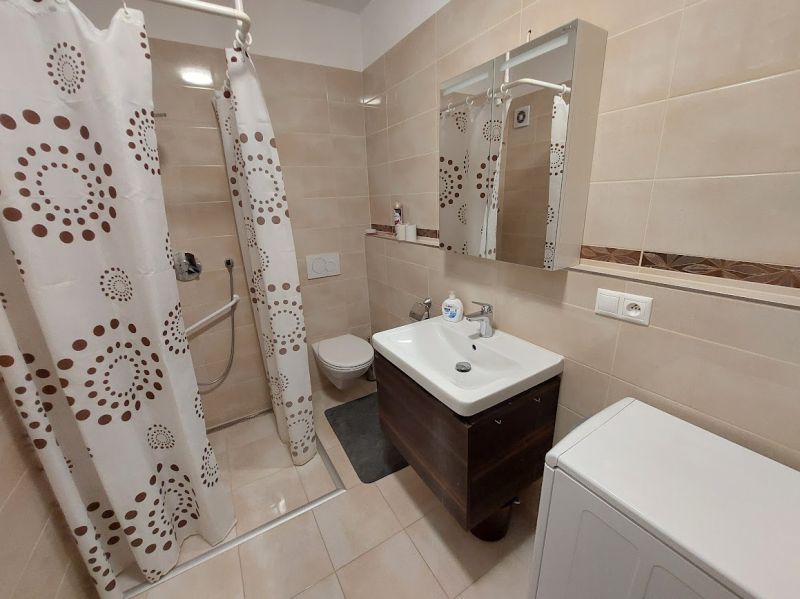 Badezimmer in einer Einzimmerwohnung mit Duschkabine, Spiegel und Waschmaschine.