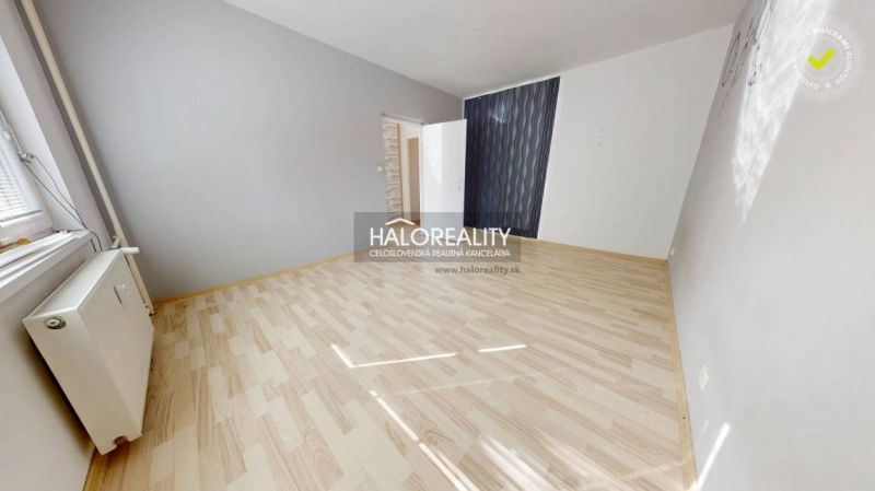 Ein Zimmer in einer Einzimmerwohnung mit einem Boden in Holzoptik und grauen Wänden.