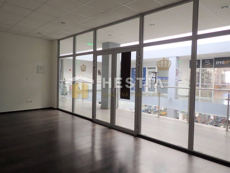 Ein leerer Raum in einer Zweizimmerwohnung mit großen Glastüren und dunklem Boden.