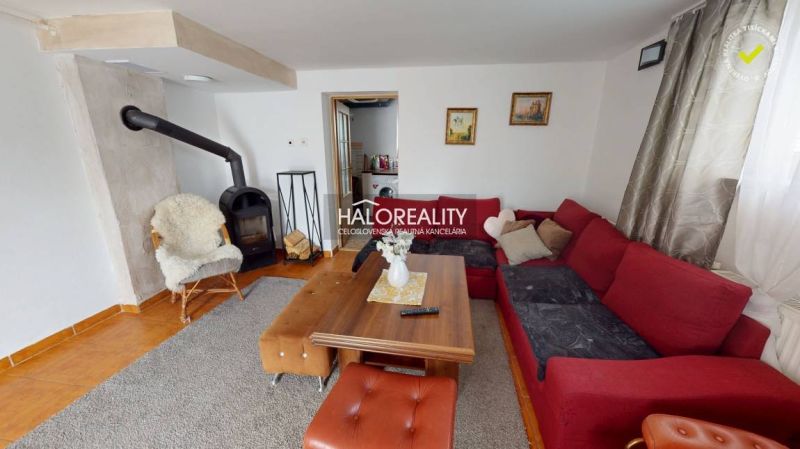 Wohnzimmer in einem Einfamilienhaus mit Kamin, bequemer Couch und Holztisch.