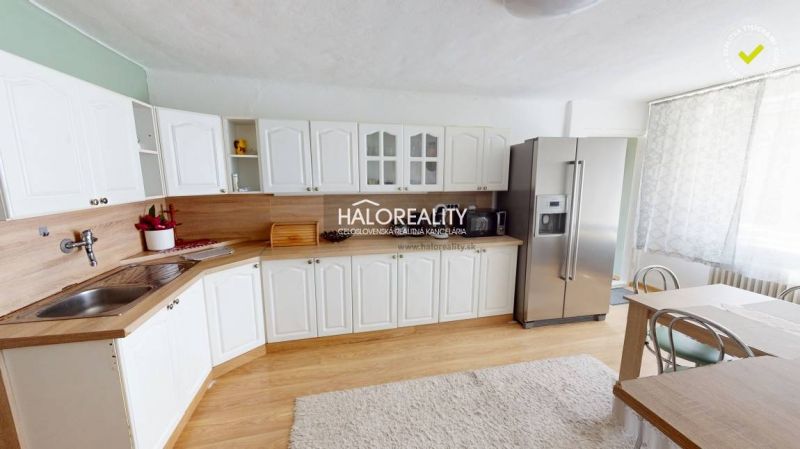 Küche in einem Einfamilienhaus mit weißen Schränken, Kühlschrank und Holzboden.