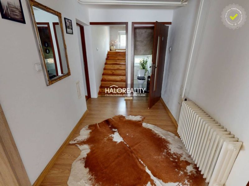 Innenraum eines Einfamilienhauses mit Holzboden und Treppe mit Geländer.