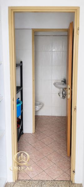 Badezimmer in Geschäftsräumen mit Toilette und Waschbecken, einfaches Fliesendesign.