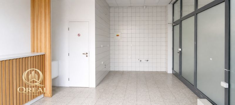 Gewerbeflächen mit hellem Boden, weißen Fliesen und Holzelementen an der Wand.