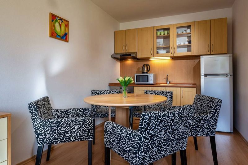 Küchenecke mit Esstisch und Stühlen im Ferienapartment, Boden mit Holzdekor.
