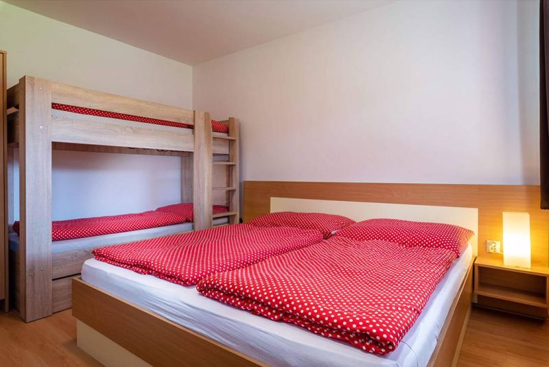 Das Ferienapartment bietet ein komfortables Schlafzimmer mit einem Etagenbett und einem Boden in Holzoptik.