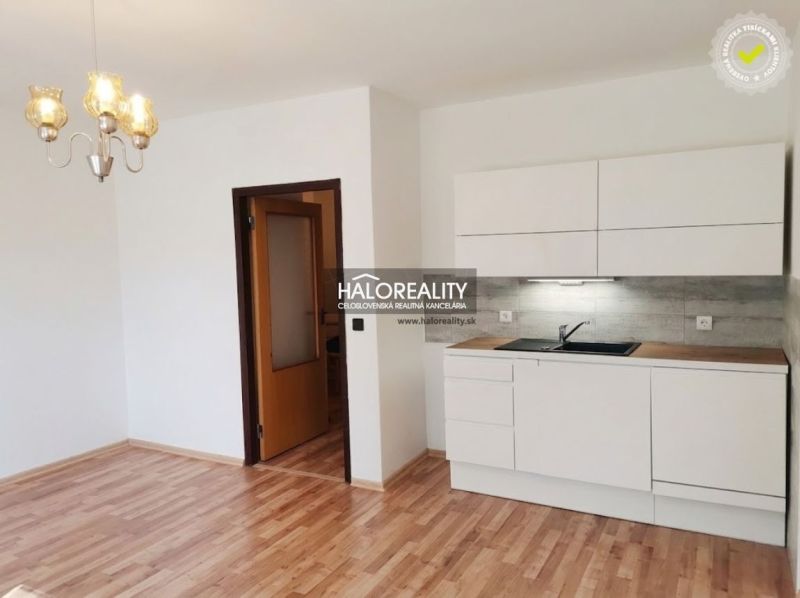 Einzimmerwohnung mit Küche, weißen Schränken und Holzboden, geeignet zur Vermietung.