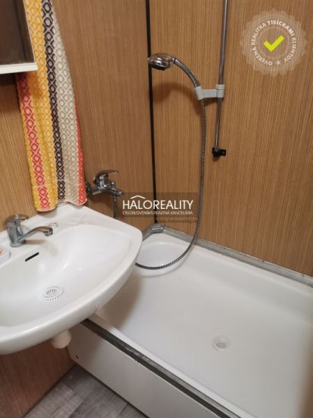 Badezimmer in einem Studio-Apartment mit Badewanne und Waschbecken, Boden mit Holzdekor.