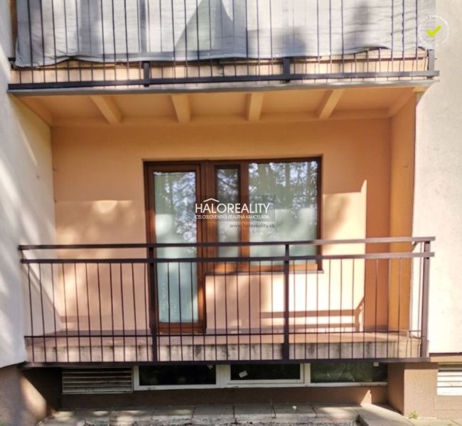 Der Balkon eines Einzimmerapartments in Myjava mit einem Metallgeländer und einer hellen Fassadenverkleidung.