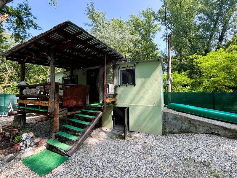 Die Holzterrasse der Hütte in Gabčíkovo, umgeben von Grünflächen und einer Kiesfläche.