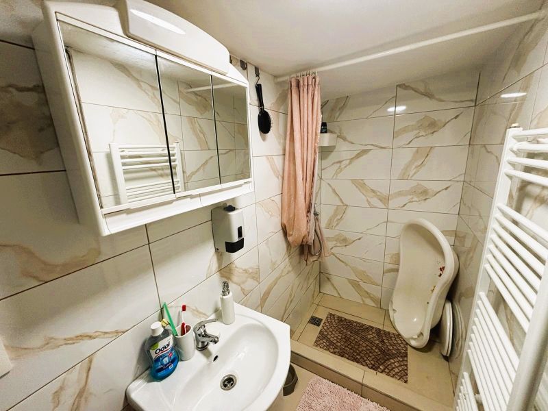 Ein Badezimmer in einer Hütte mit einem weißen Waschbecken, einem Spiegelschrank und einer Duschkabine.