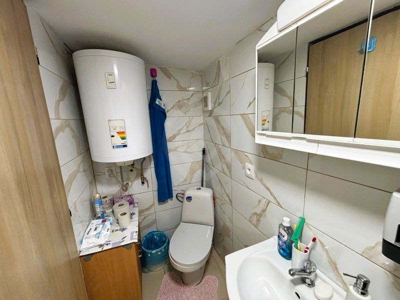 Ein Badezimmer mit Fliesen und Boiler bietet grundlegende Hygieneartikel und Stauraum.
