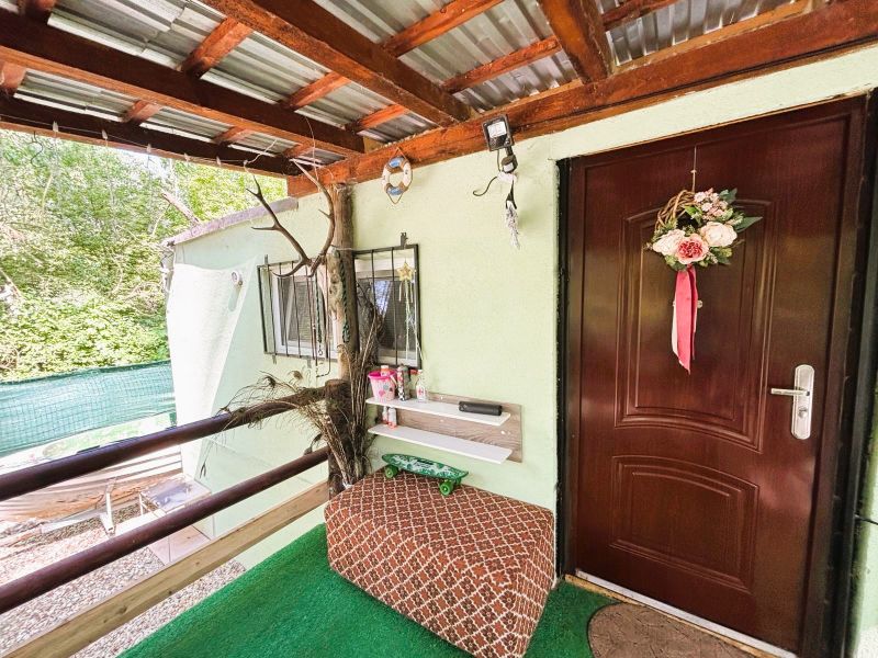 Eine Hütte in Gabčíkovo mit dekorativem Eingang, Geländer und Sitzbereich in der Nähe einer Grünfläche.