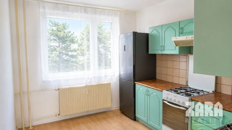 Küche in einer 4-Zimmer-Wohnung mit einem Gasherd, einem schwarzen Kühlschrank und Holzelementen.