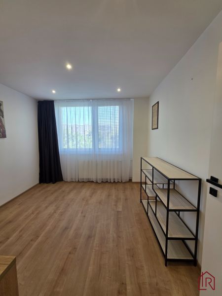 Ein Zimmer mit einem Holzboden und einem Regal in einer 3-Zimmer-Wohnung.