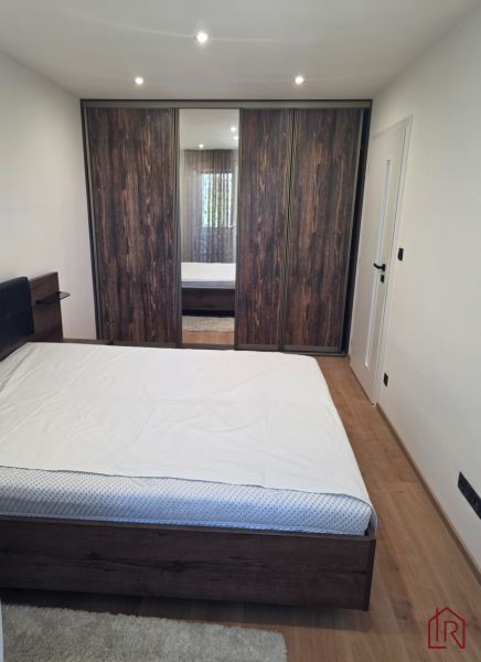Schlafzimmer mit großem Schrank, Bett und Boden mit Holzdekor in einer 3-Zimmer-Wohnung.