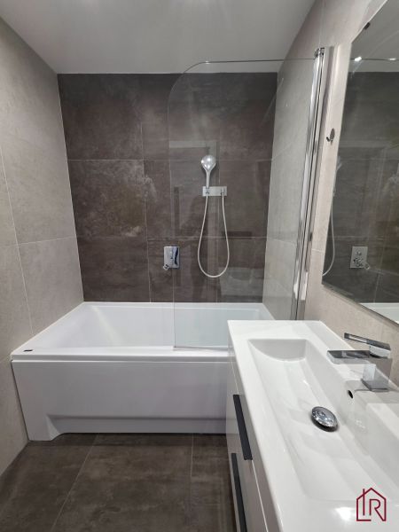 Badezimmer in einer 3-Zimmer-Wohnung mit Badewanne, Duschwand und modernem Waschbecken.