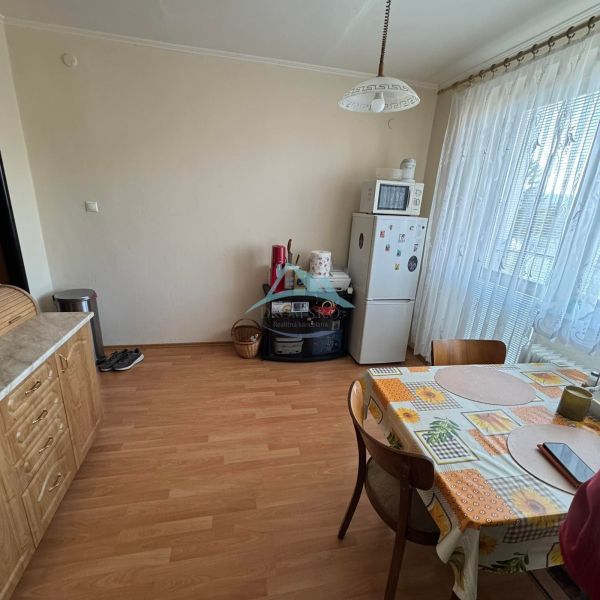 Küche in einer Einzimmerwohnung mit Holzboden, Esstisch und Geräten.