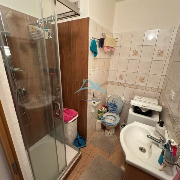Badezimmer mit Dusche und Fliesen in einer Einzimmerwohnung.
