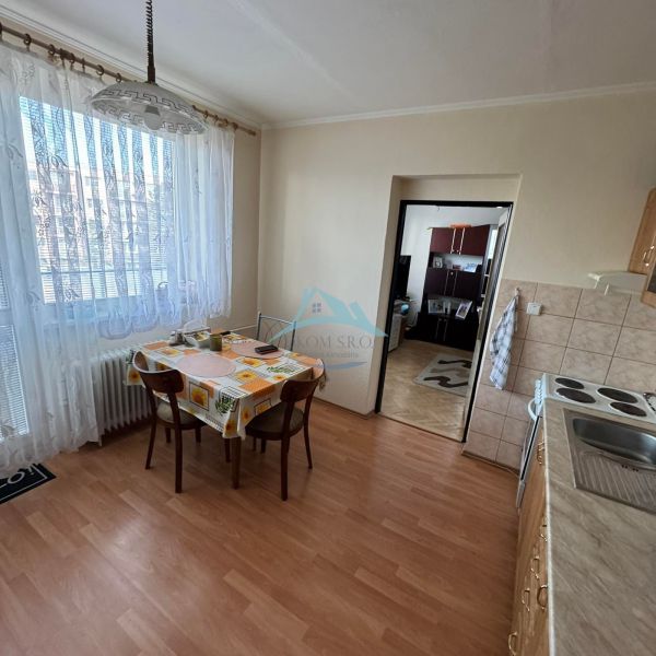 Küche in einer Einzimmerwohnung mit Holzboden und Esstisch.