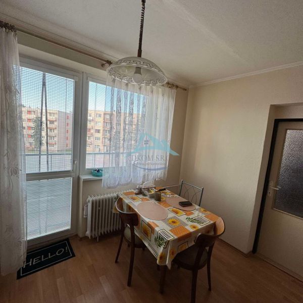 Essbereich mit Fenster und Tisch in einer Einzimmerwohnung, Boden mit Holzdekor.