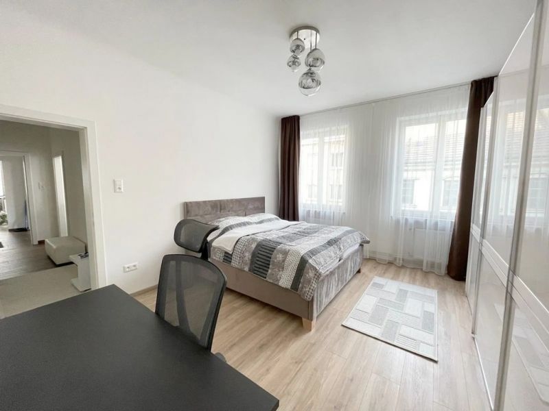 Helles Schlafzimmer mit Holzdekorboden und Schreibtisch in einer 3-Zimmer-Wohnung.