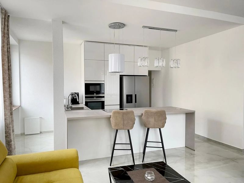 Küche in einer 3-Zimmer-Wohnung mit Insel, Barhockern und hellen Schränken.
