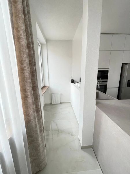 Küche in einer 3-Zimmer-Wohnung mit weißen Schränken und Marmorboden.