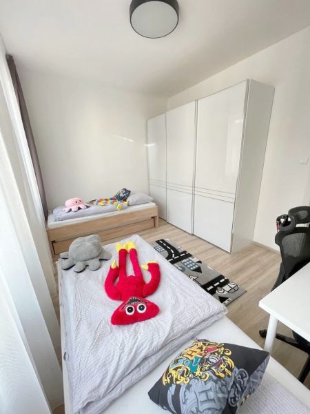 Kinderzimmer in einer 3-Zimmer-Wohnung mit Spielzeug und einem Boden in Holzoptik.