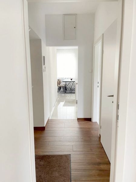 Der Flur der 3-Zimmer-Wohnung mit einem Holzboden führt ins Esszimmer.