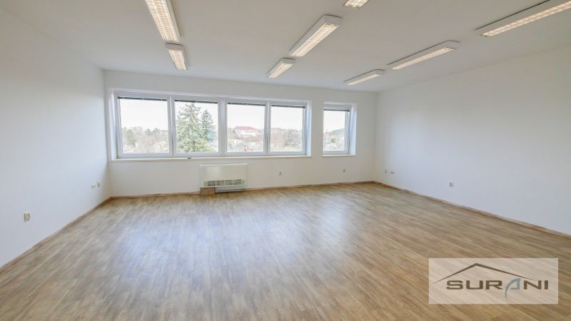 Ein geräumiges Büro mit einem Holzboden und großen Fenstern.