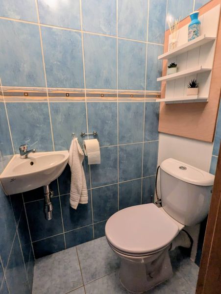 Badezimmer mit blauen Fliesen und Toilette in einer 2-Zimmer-Wohnung, Regale an der Wand.