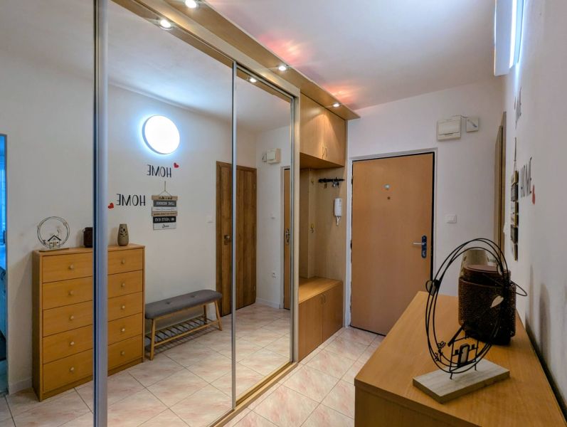 Der Flur einer 2-Zimmer-Wohnung mit einem großen Schrank, Eingangstüren und Dekorationen.