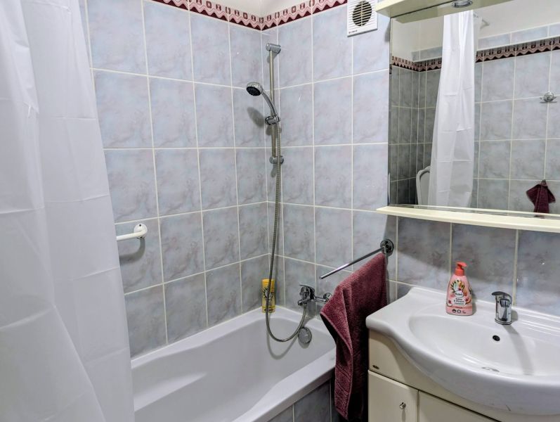 Badezimmer in einer 2-Zimmer-Wohnung mit Badewanne, Waschbecken und Keramikfliesen.