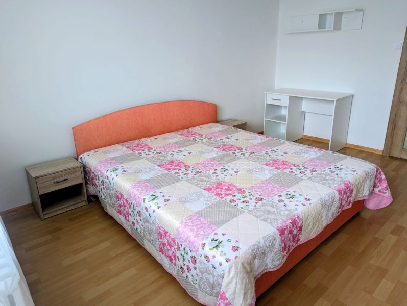Schlafzimmer in einer 2-Zimmer-Wohnung mit Bett, Schreibtisch und Holzboden.