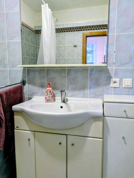 Badezimmer in einer 2-Zimmer-Wohnung mit Waschbecken, Spiegel und blauen Fliesen.
