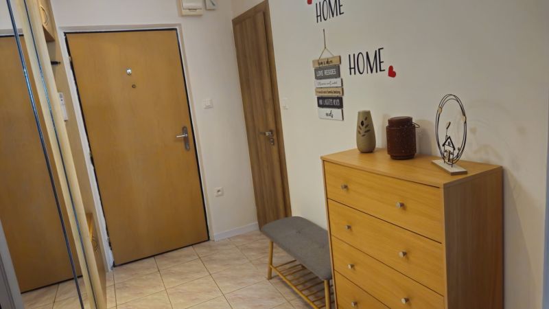 Der Flur in der 2-Zimmer-Wohnung mit einer Kommode, einem Spiegel und Wanddekorationen.