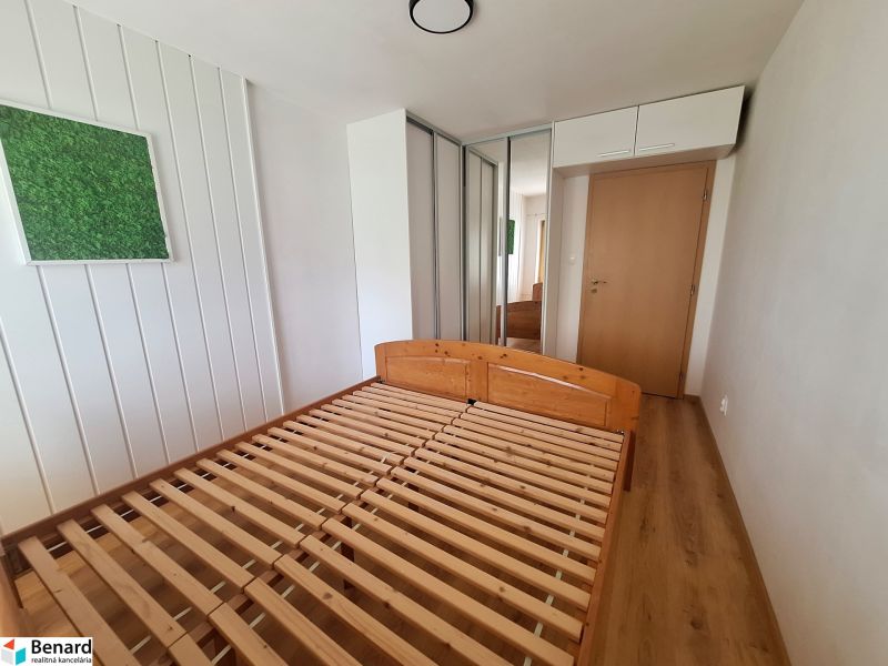 Schlafzimmer in einer 2-Zimmer-Wohnung mit einem Holzbett, einem Einbauschrank und Wanddekoration.