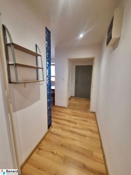 Der Flur in der 2-Zimmer-Wohnung mit Holzboden und einem Regal an der Wand.
