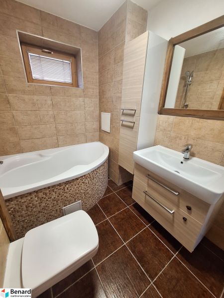 Badezimmer mit Eckbadewanne, Waschbecken und Toilette in einer 2-Zimmer-Wohnung.