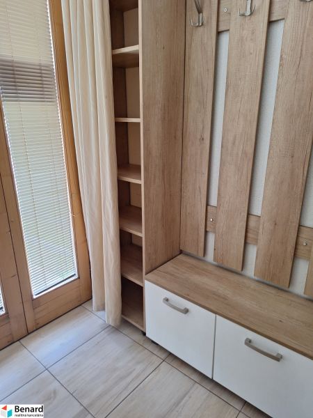 Ein hölzerner Kleiderständer mit Stauraum am Fenster in einer 2-Zimmer-Wohnung.